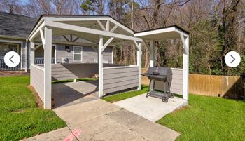 a backyard barbecue pit with a house in the background