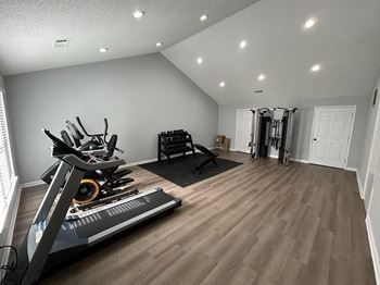a home gym with a treadmill and weights on a wooden floor