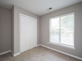 an empty bedroom with a large window and a white door