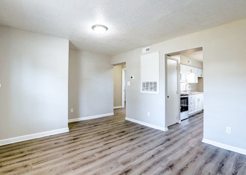 an empty living room and kitchen with wood flooring