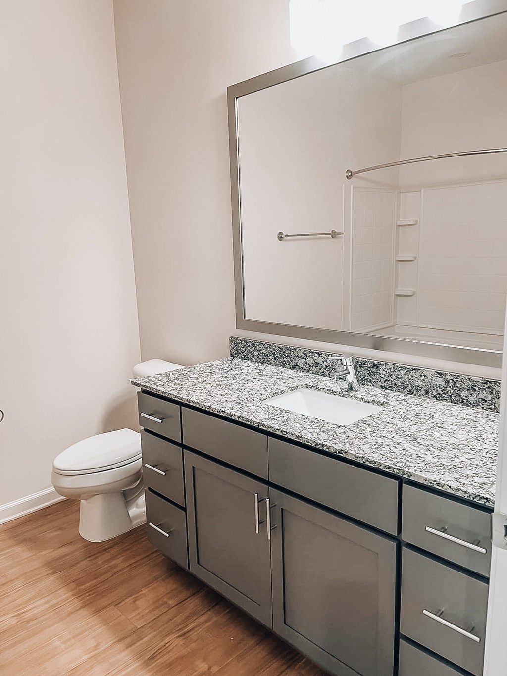 A bathroom with a toilet, sink and mirror.at Evolve at Parkway Apartment Homes, Concord