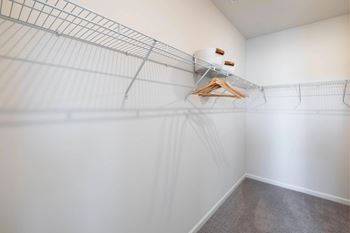 A wire shelving unit with clothes hangers is in a room with white walls.
