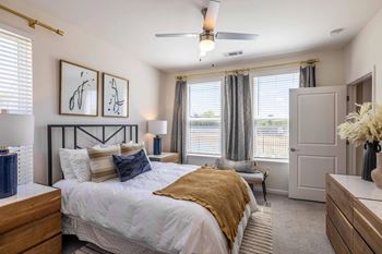 A bedroom with a bed, dresser, and a ceiling fan.