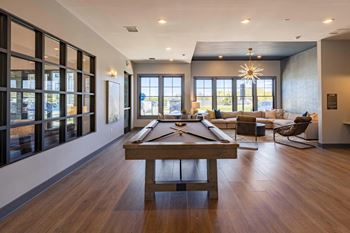 A pool table is in the middle of a room with a view of the outside.