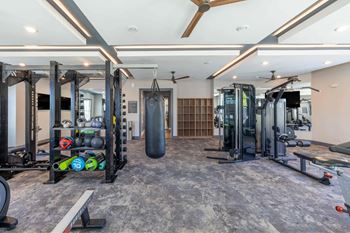 A spacious gym with a variety of equipment including a punching bag, weight racks, and a bench.
