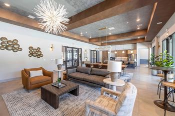 A modern living room with a large chandelier and a variety of seating options.