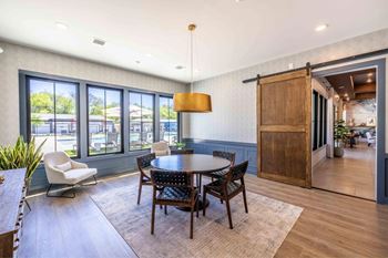 A dining room with a table and chairs and a view of the outside.