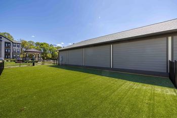 A large grassy area in front of a building with a closed grey garage door.