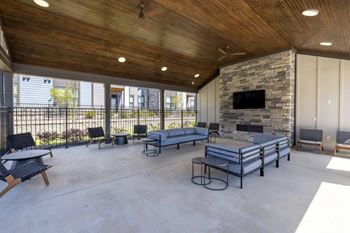 A modern outdoor living space with a stone fireplace and comfortable seating.