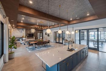 A modern kitchen with a large island and pendant lights.