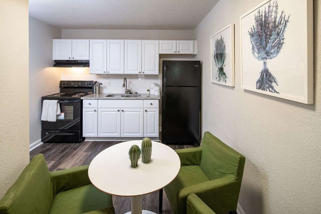 a kitchen and living room with green chairs and a table at Viceroy Apartments, Durham , NC