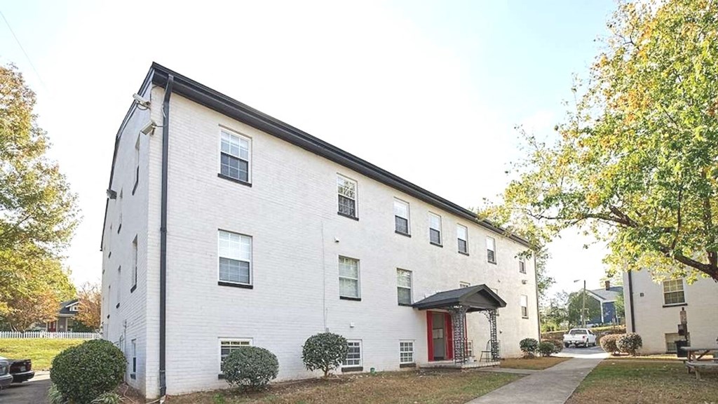 a white brick building with a red door at Viceroy Apartments, Durham , NC 27707