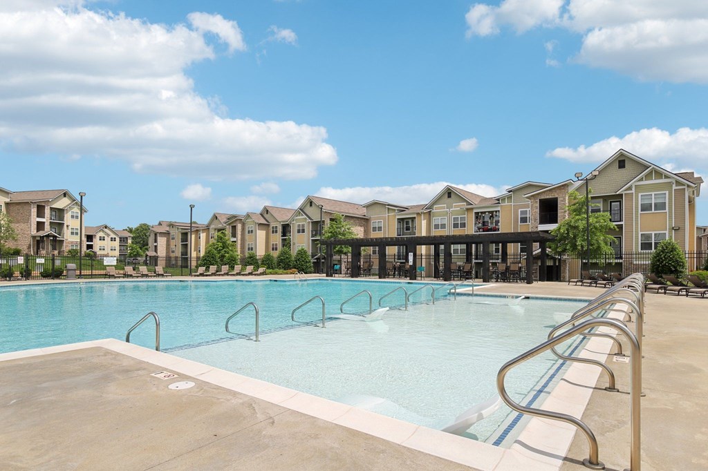 A large swimming pool with a concrete edge and metal handrails is surrounded by apartment buildings at Venue at 109 Apartments, Tennessee