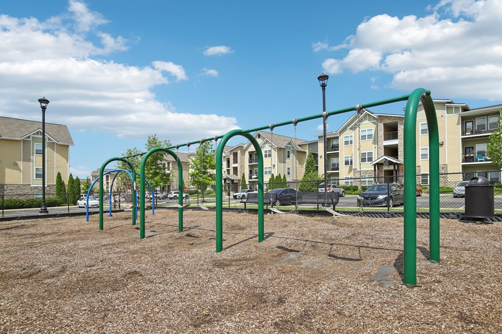A playground with a green swing set in the middle of a gravel area at Venue at 109 Apartments, Lebanon , TN, 37090