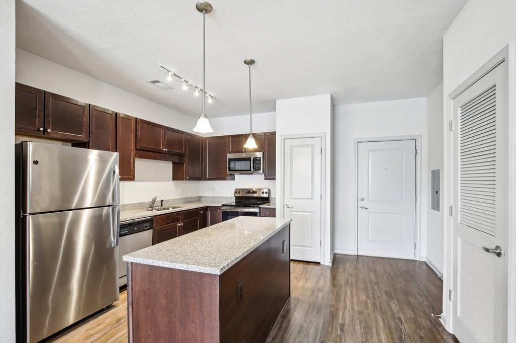 A kitchen with a stainless steel refrigerator and wooden cabinets at Venue at 109 Apartments, Tennessee