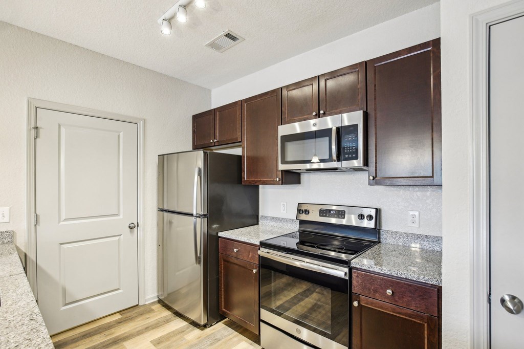A kitchen with brown cabinets and stainless steel appliances. at Venue at 109 Apartments, Tennessee, 37090