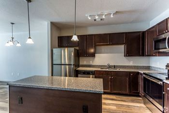 a kitchen with dark wood cabinets and granite countertops at The Venue at 109 Apartments , Lebanon, Tennessee