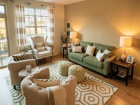 A living room with a green couch and a white chair.