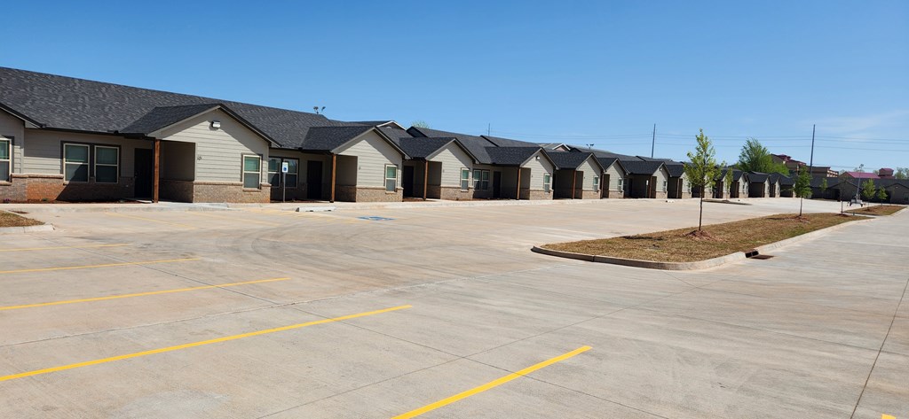 A parking lot with a few cars and a building in the background.