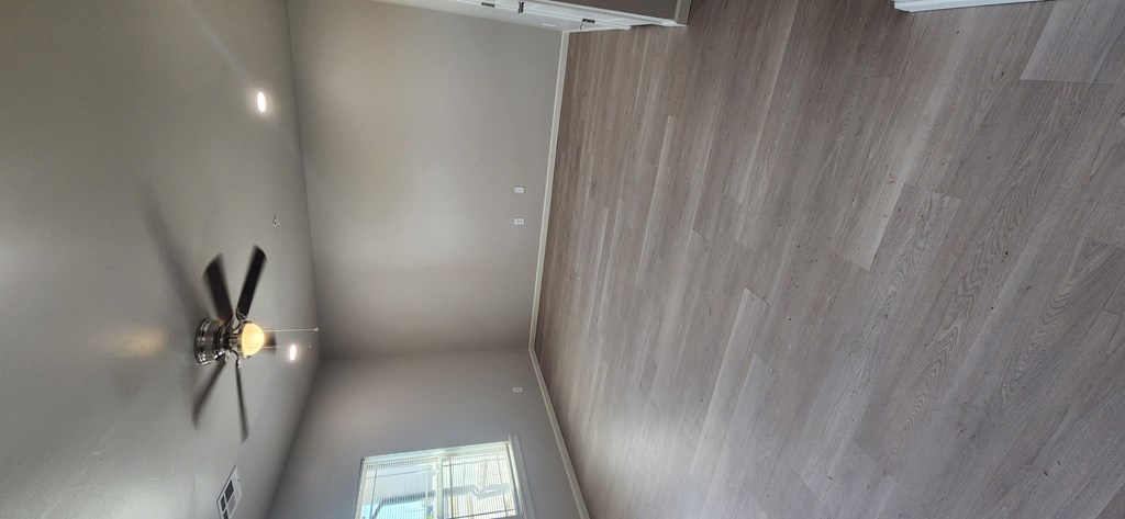 A ceiling fan is mounted on a wall in a room with wood paneling.