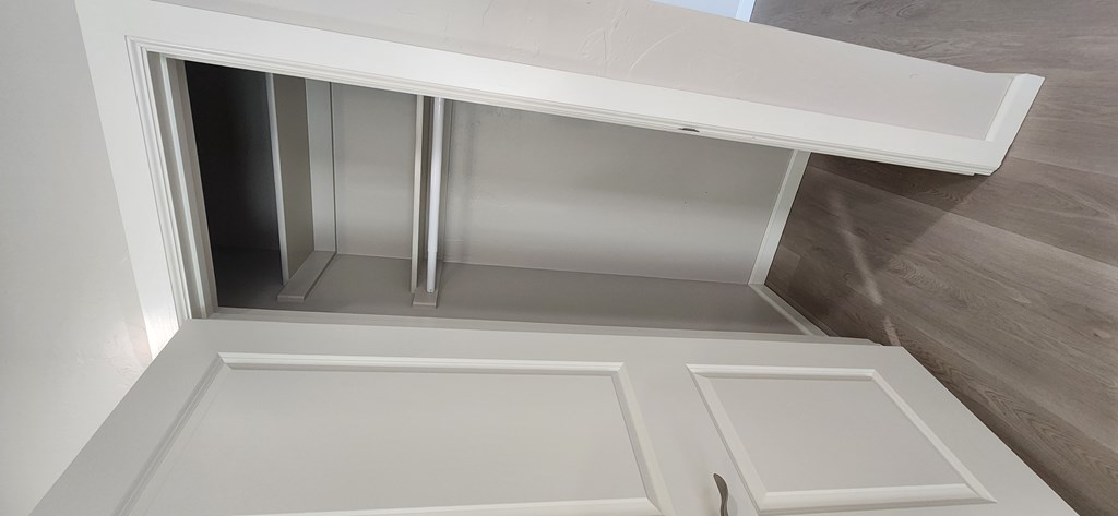 A white cabinet with a door open revealing shelves inside.
