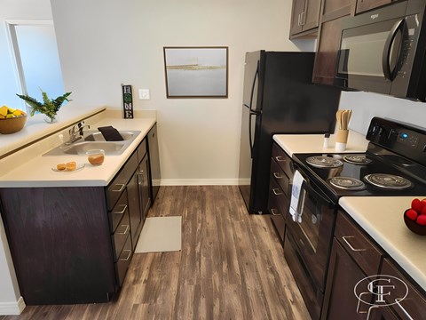 A kitchen with a black fridge and wooden floors.