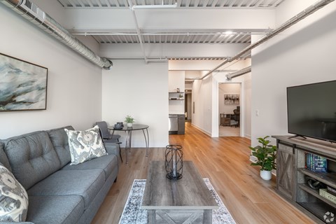 A living room with a grey couch and a glass coffee table.