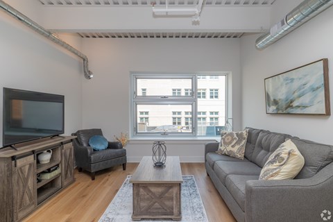 A living room with a grey couch, a wooden cabinet, a chair, and a coffee table.