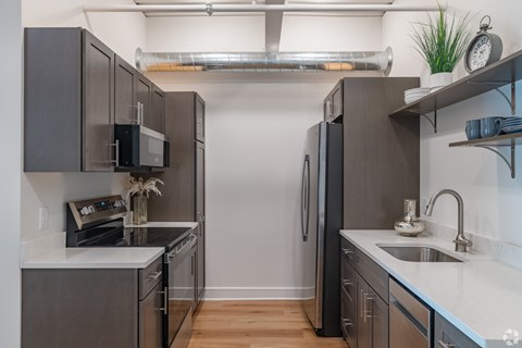 A modern kitchen with dark grey cabinets and stainless steel appliances.