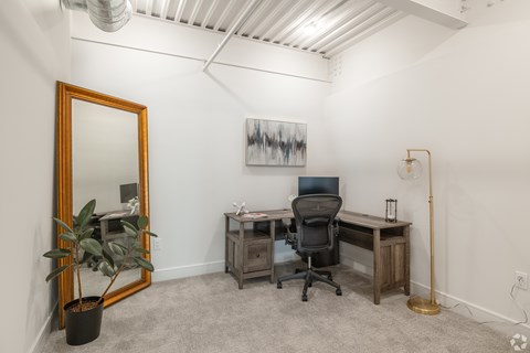 A room with a desk, chair, and a painting on the wall.