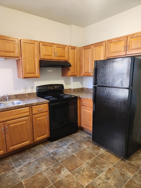 A kitchen with black appliances and wooden cabinets.