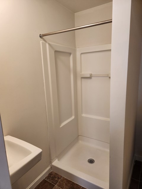 A white bathroom with a toilet and a walk in shower.