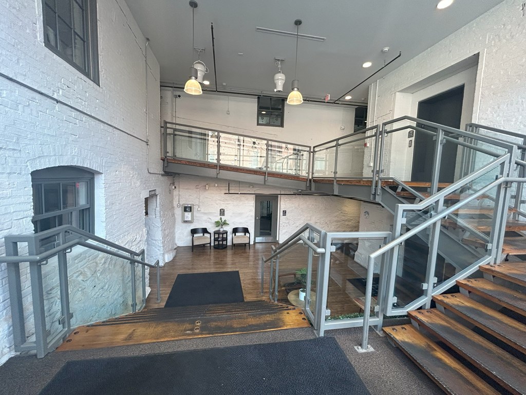 A staircase with a metal railing and a black mat on the floor.