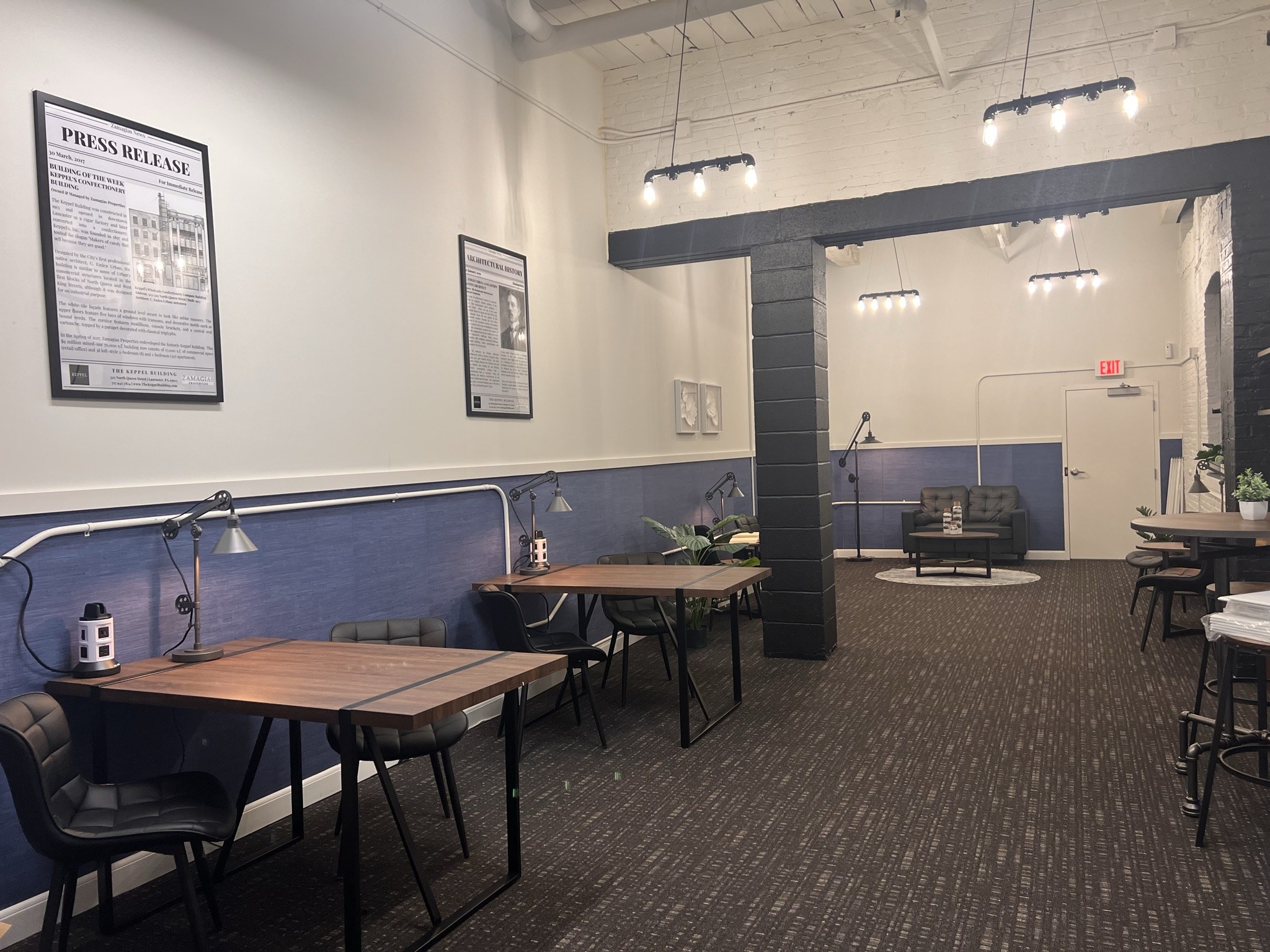 A room with a long table and chairs, a couch, and a poster on the wall.