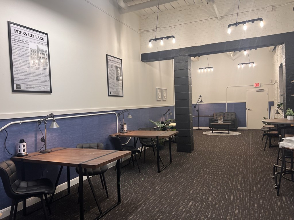 A room with a long table and chairs, a couch, and a poster on the wall.