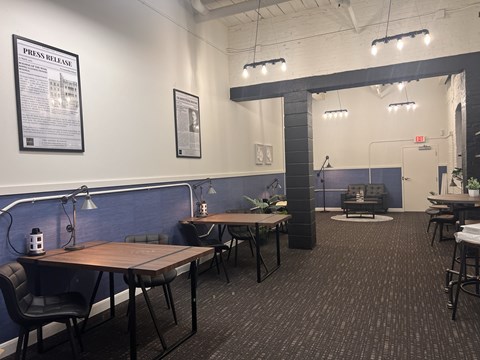 A room with a long table and chairs, a couch, and a poster on the wall.