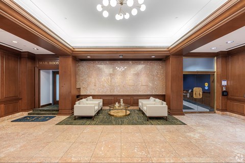 A spacious lobby with a marble floor and a chandelier hanging from the ceiling.