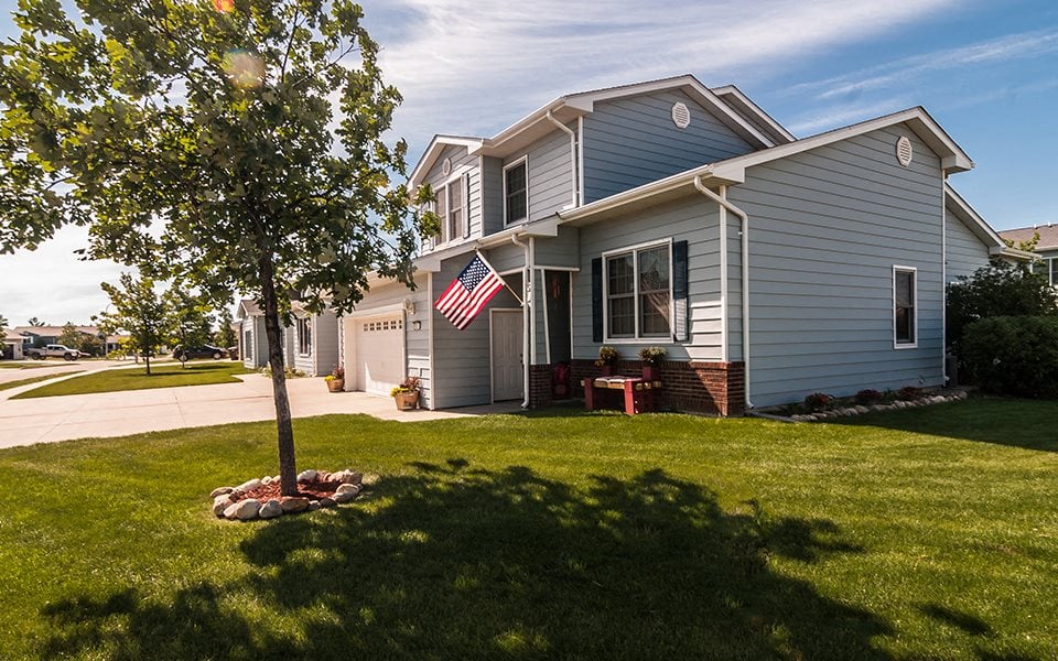 a blue house with an flag on the lawn