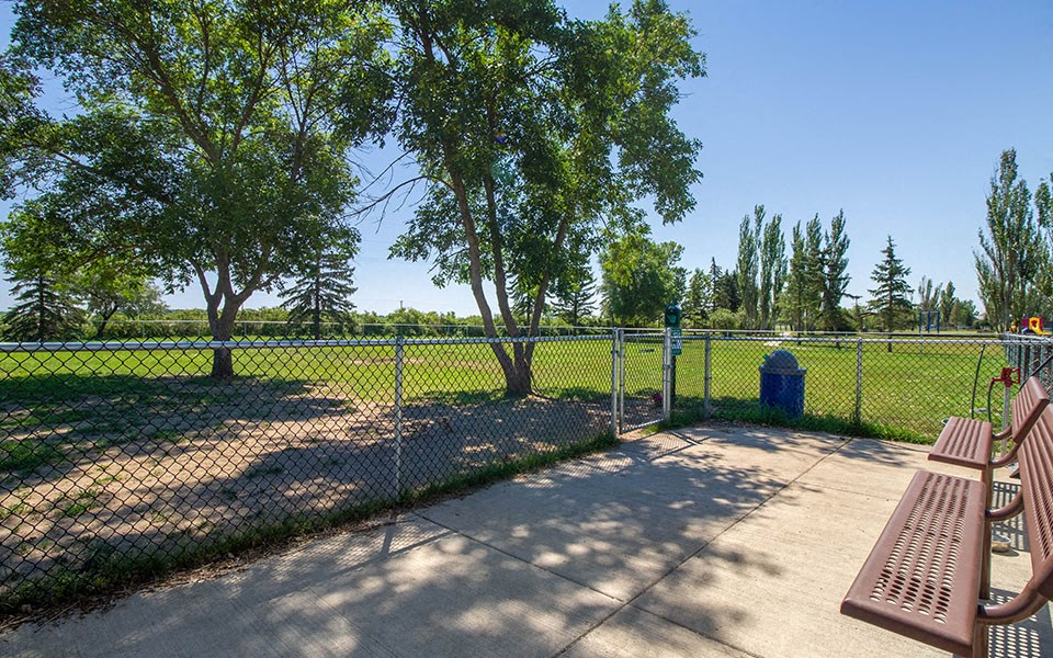 a park bench on a sidewalk next to a fence