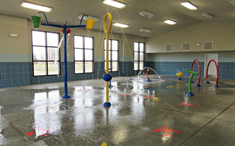 a childrens play area in a multipurpose room with water jets and toys