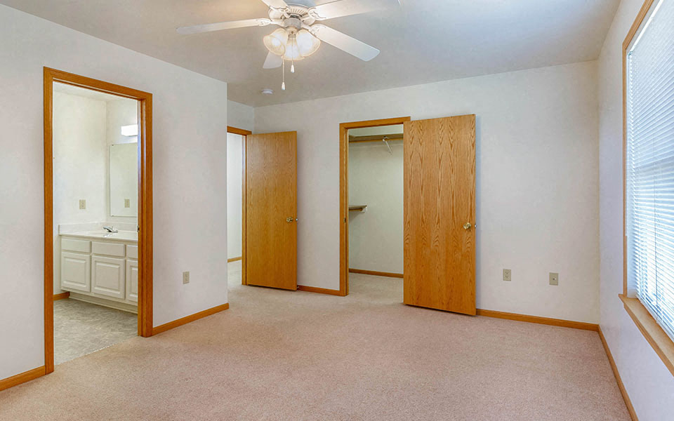 an empty living room with a ceiling fan and a bathroom