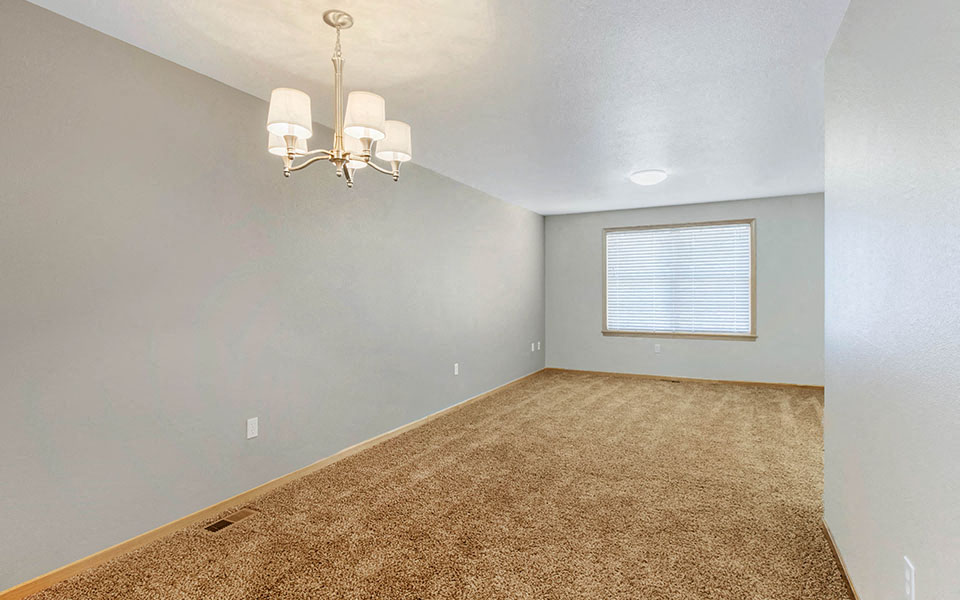 an empty living room with a chandelier and a window