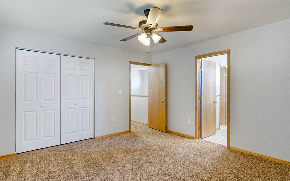 an empty bedroom with a ceiling fan and a closet