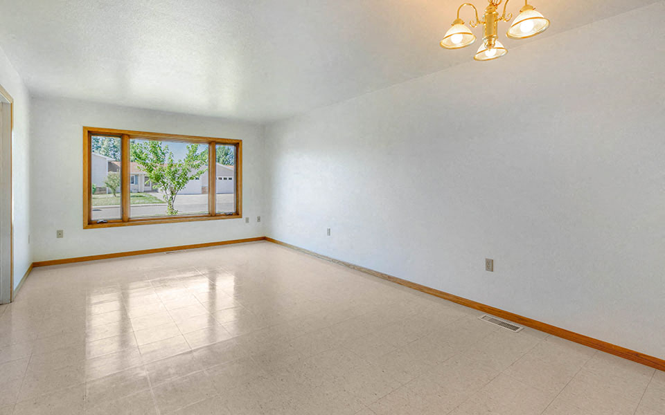 an empty living room with a large window and a tiled floor
