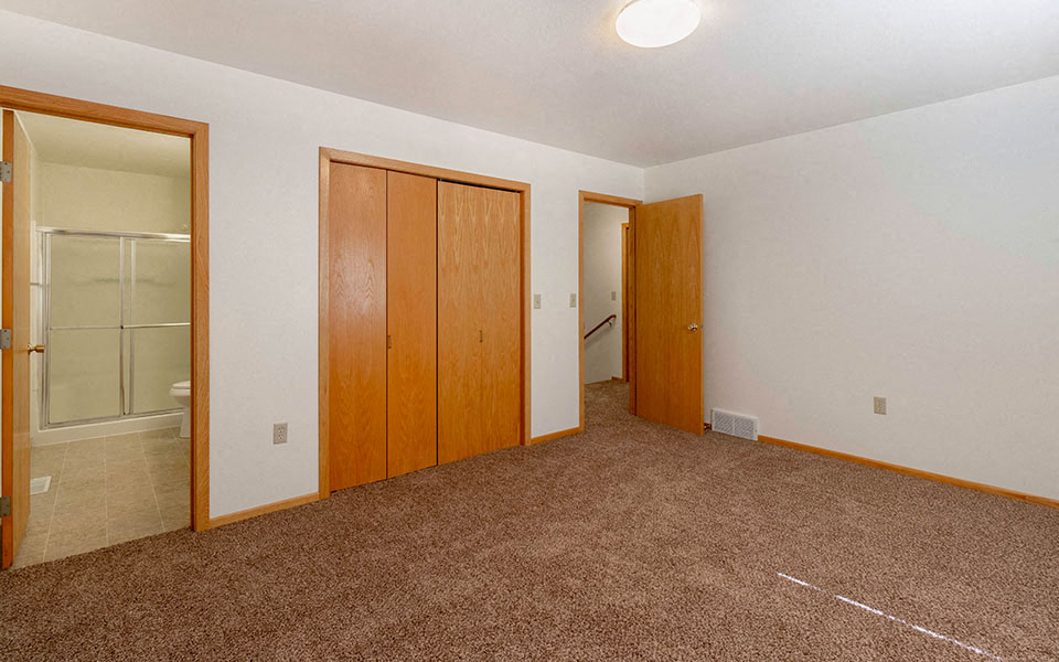 a bedroom with a carpeted floor and a door to a bathroom