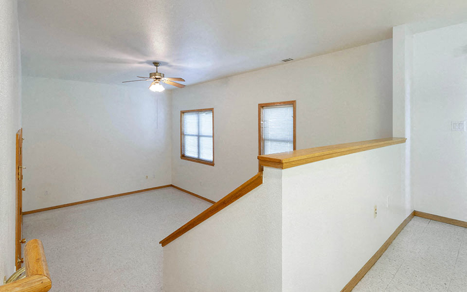 a living room with white walls and a ceiling fan