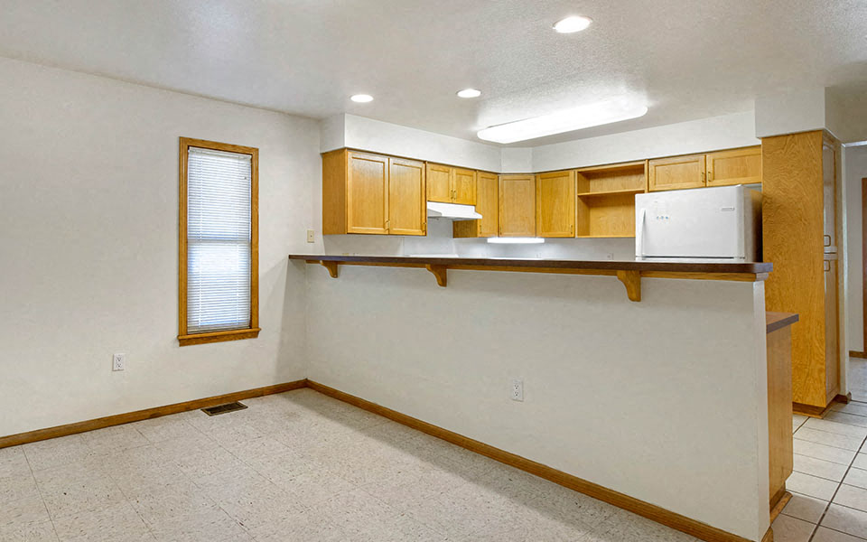 an empty kitchen with a counter and a refrigerator