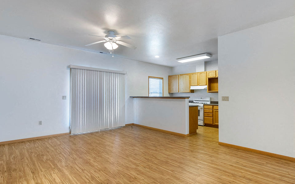 an empty living room and kitchen with a ceiling fan