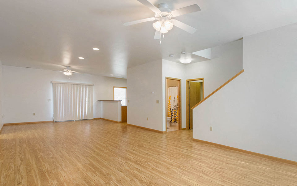 an empty living room with a ceiling fan and wood floors