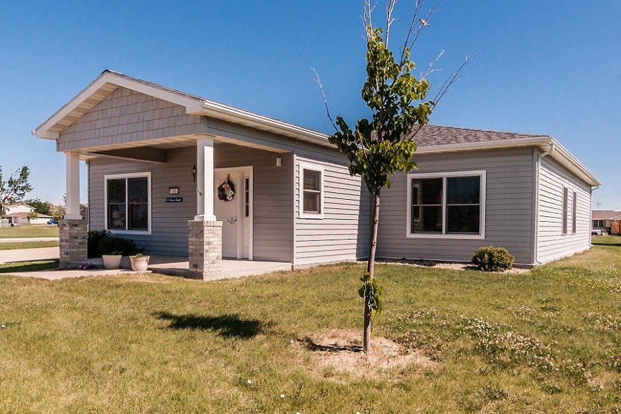 a small gray house with a tree in front of it